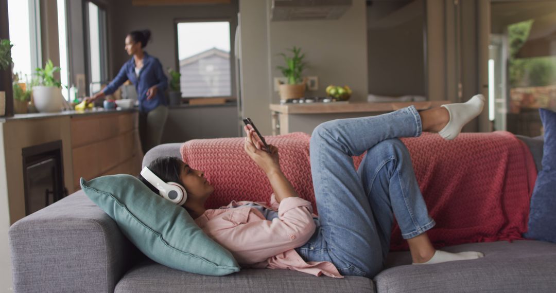 Woman Relaxing on Sofa Using Smartphone with Headphones - Free Images, Stock Photos and Pictures on Pikwizard.com