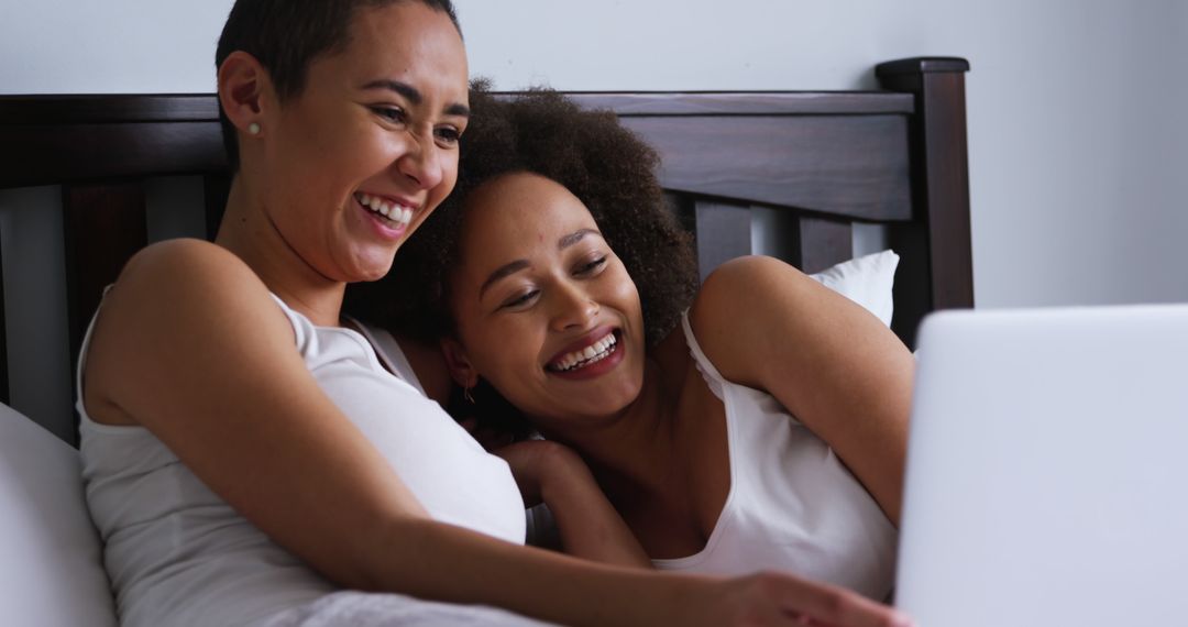 Happy Lesbian Couple Relaxing on Bed Using Laptop