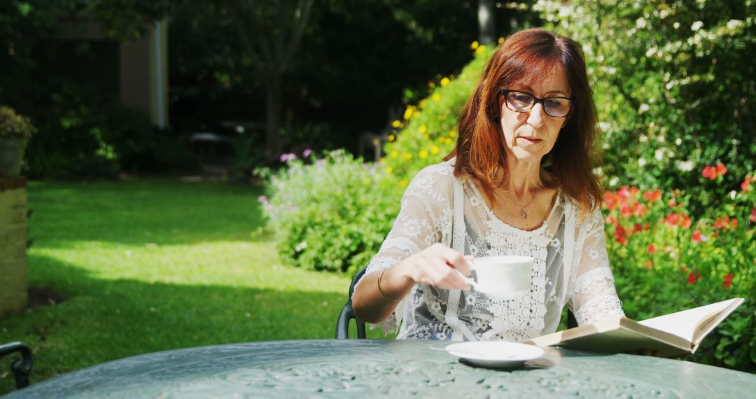 Woman reading and drinking coffee in sunny garden - Free Images, Stock Photos and Pictures on Pikwizard.com