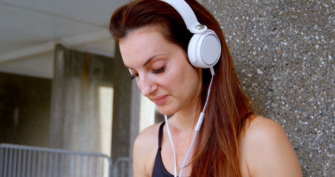 Woman listening to music with white headphones outdoors - Free Images, Stock Photos and Pictures on Pikwizard.com