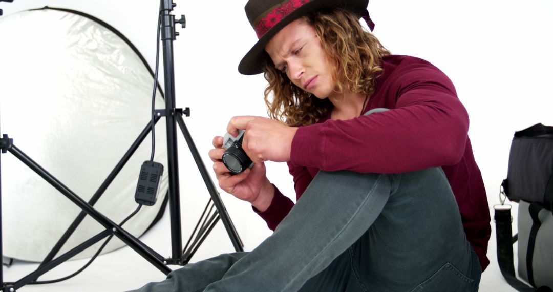 Young Photographer Checking Camera Settings in Studio - Free Images, Stock Photos and Pictures on Pikwizard.com