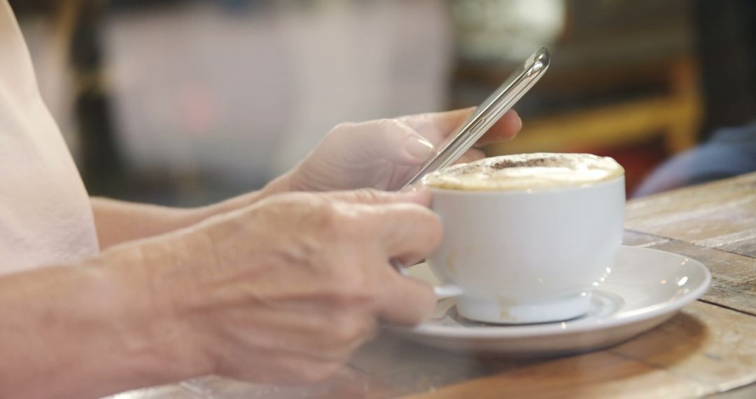 Person Using Smartphone While Enjoying Coffee in Cafe - Free Images, Stock Photos and Pictures on Pikwizard.com