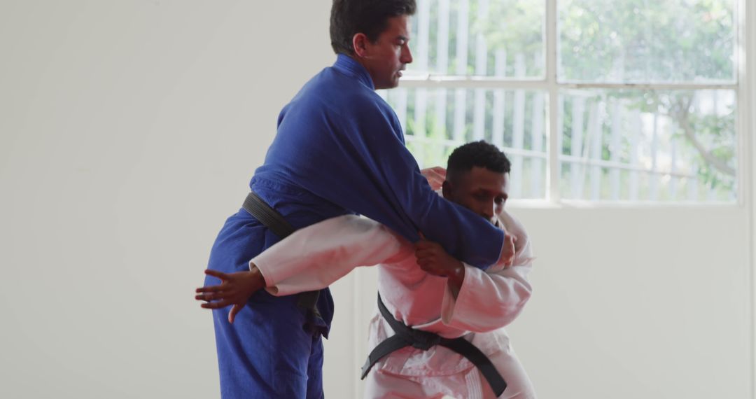 Two Martial Artists Practicing Judo Inside Bright Spacious Room - Free Images, Stock Photos and Pictures on Pikwizard.com