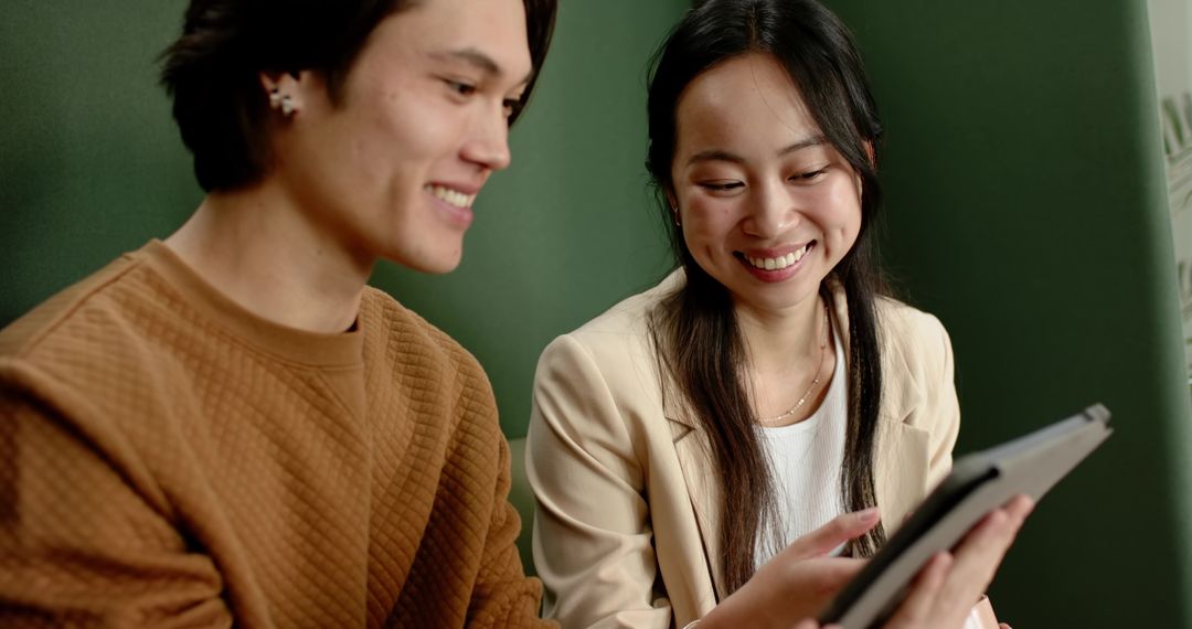 Asian Coworkers Collaborating with Tablet in Modern Office