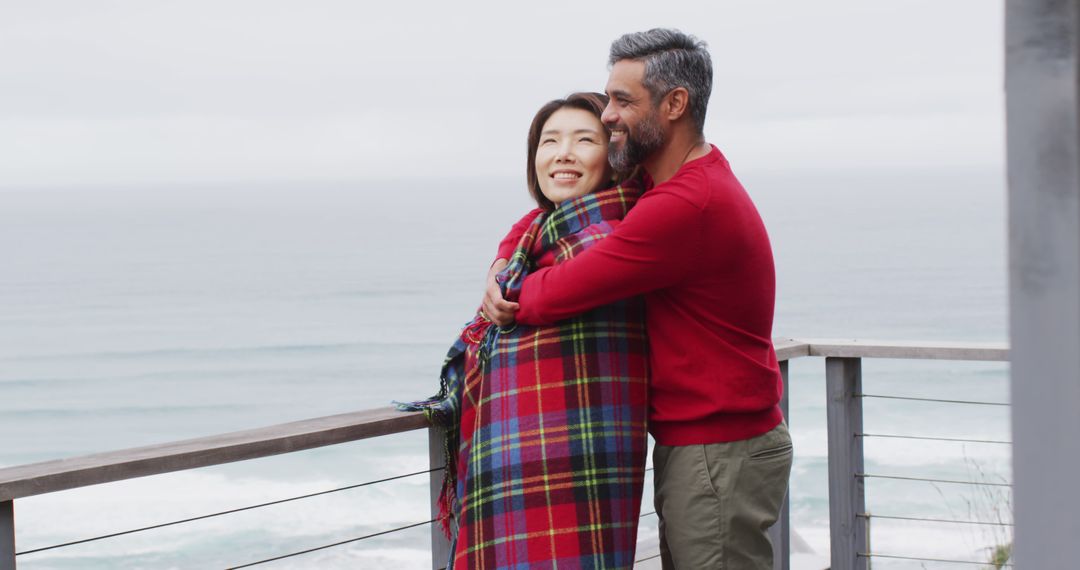 Smiling Couple Embracing on Balcony Overlooking Ocean, Wrapped in Blanket - Free Images, Stock Photos and Pictures on Pikwizard.com