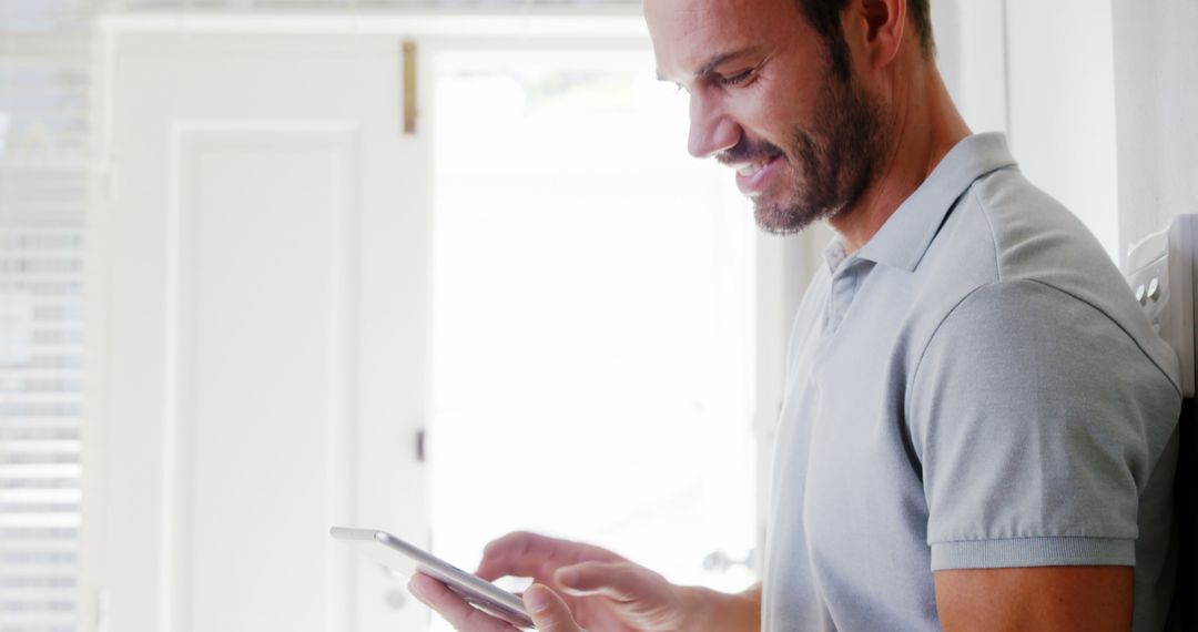 Smiling Man Using Tablet in Bright Room - Free Images, Stock Photos and Pictures on Pikwizard.com