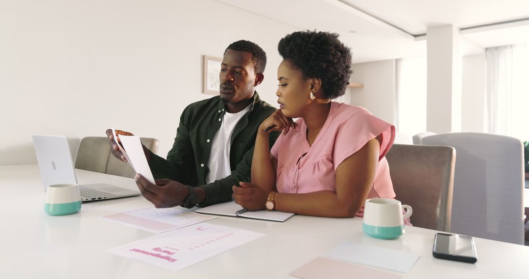 Focused Team Collaborating Over Laptop and Notes at Home
