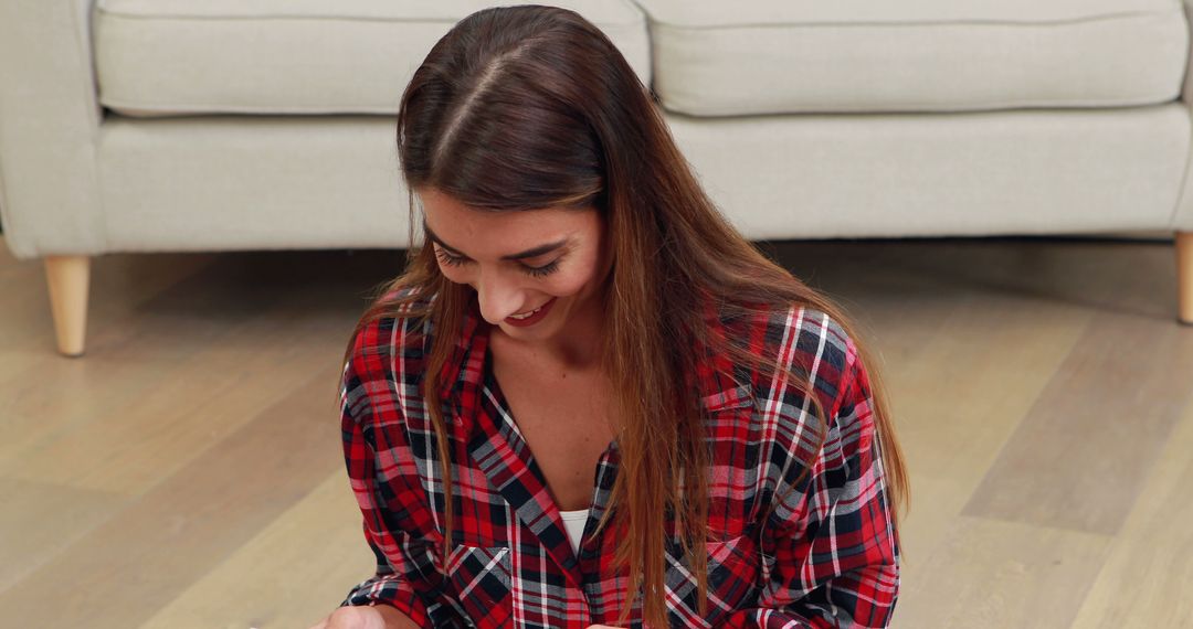 Smiling Young Woman in Plaid Shirt Sitting on Floor - Free Images, Stock Photos and Pictures on Pikwizard.com