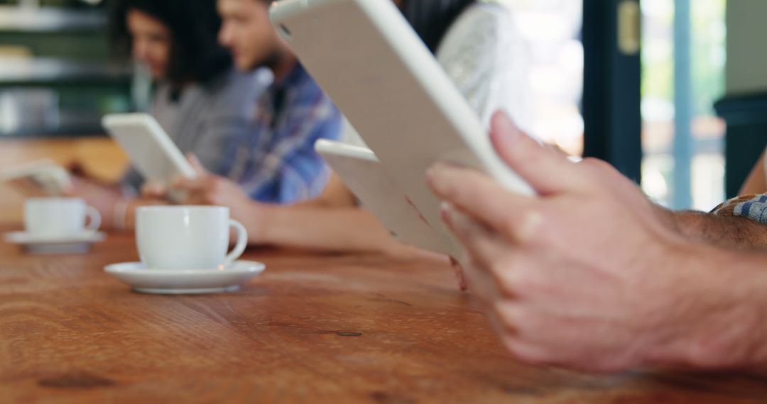 Group of People Using Tablets and Drinking Coffee in Cafe - Free Images, Stock Photos and Pictures on Pikwizard.com