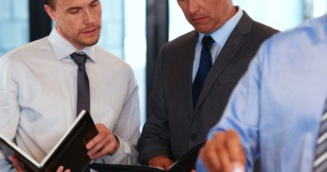 Businessmen Discussing Documents in Office Meeting - Free Images, Stock Photos and Pictures on Pikwizard.com