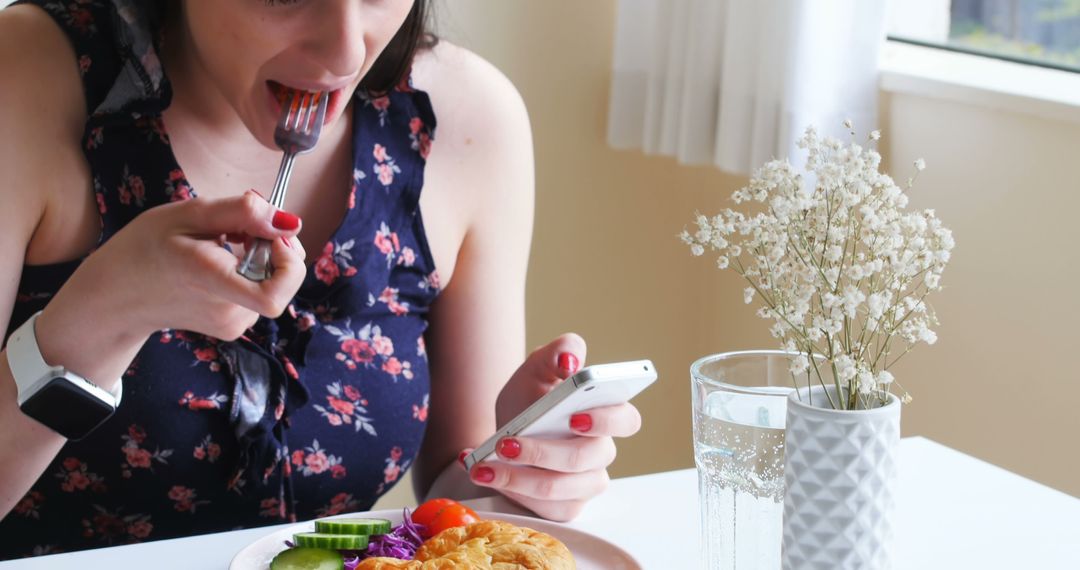 Woman Eating Healthy Meal While Using Smartphone in Bright Dining Room - Free Images, Stock Photos and Pictures on Pikwizard.com