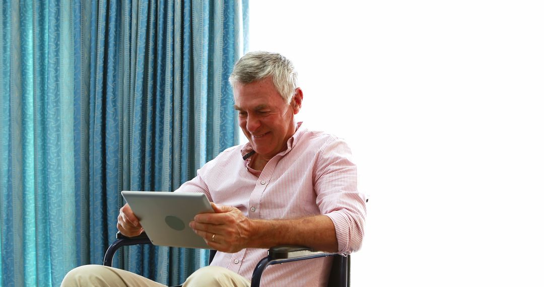 Senior Man Using Digital Tablet and Smiling While Sitting Indoors - Free Images, Stock Photos and Pictures on Pikwizard.com