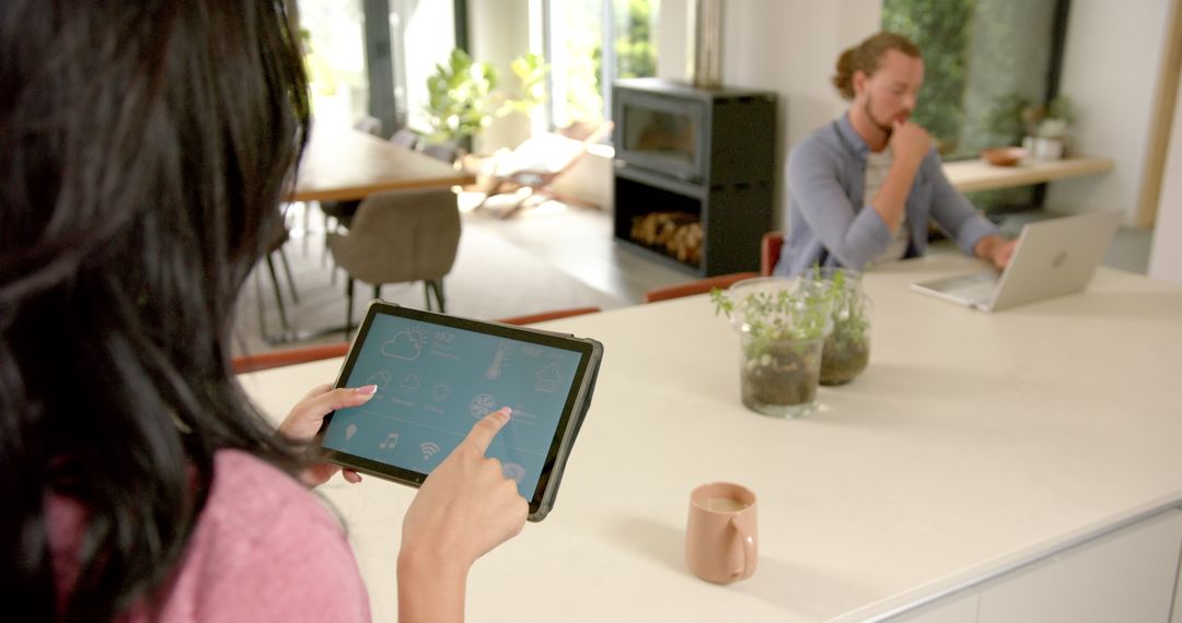 Young Woman Managing Smart Home App on Tablet While Partner Works Remotely