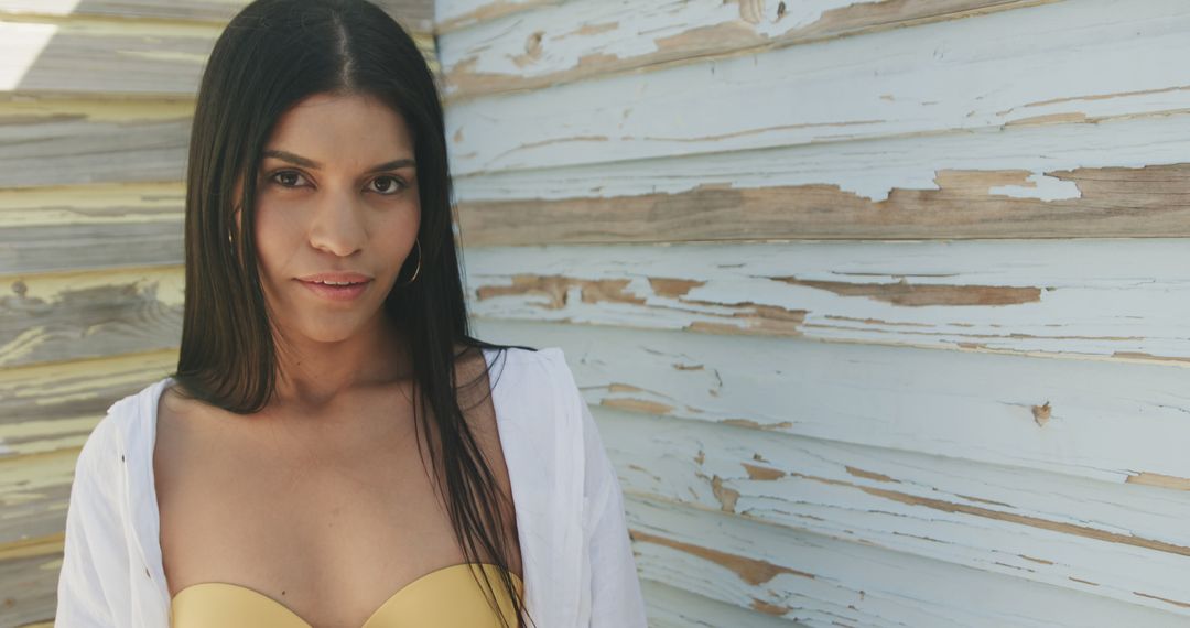 Confident Woman in Yellow Top Posing Against Weathered Wooden Wall - Free Images, Stock Photos and Pictures on Pikwizard.com