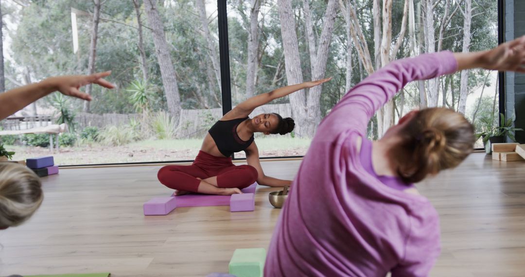 Yoga Instructor Leading a Stretching Session in Modern Studio - Free Images, Stock Photos and Pictures on Pikwizard.com