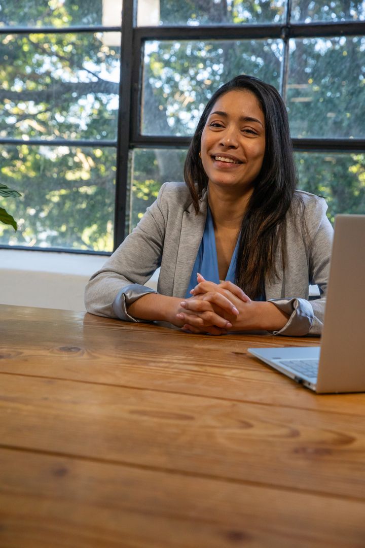 Confident Businesswoman Working at Wooden Table with Laptop