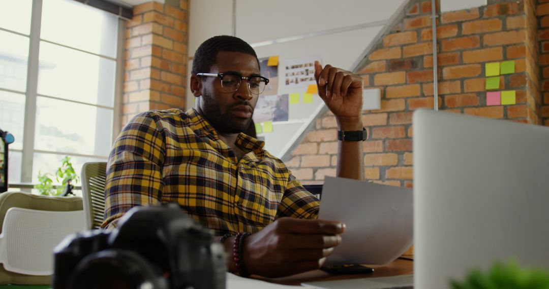 Focused Creative Professional Analyzing Photographs in Modern Office