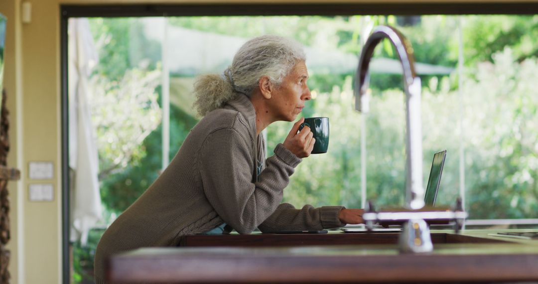 Senior Woman Enjoying Coffee While Working on Laptop - Free Images, Stock Photos and Pictures on Pikwizard.com