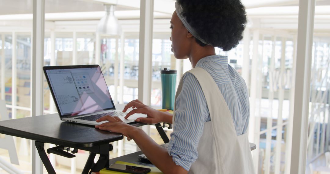 Young Woman Using Laptop at Standing Desk in Modern Office - Free Images, Stock Photos and Pictures on Pikwizard.com