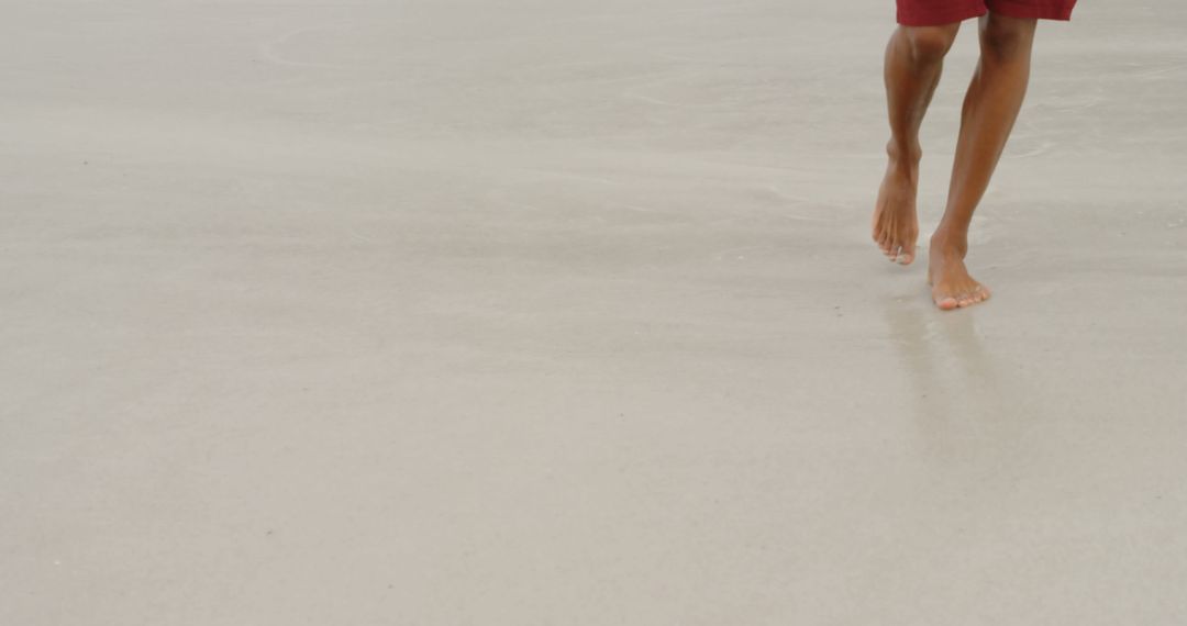 Person Walking Barefoot on Beach Sand Under Clear Sky