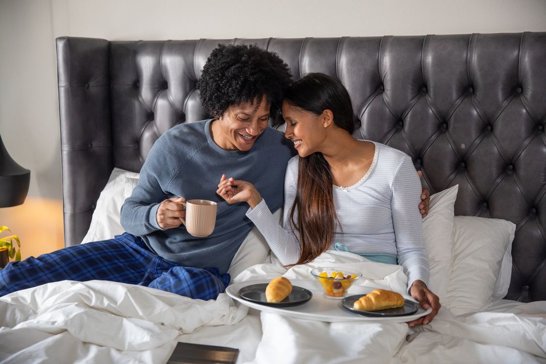 Couple Enjoying Breakfast in Bed with Croissants and Coffee