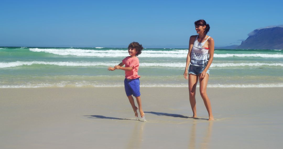 Mother and Child Enjoying Sunny Day at Beautiful Beach - Free Images, Stock Photos and Pictures on Pikwizard.com