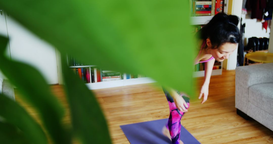 Woman Practicing Yoga at Home Behind Green Plant - Free Images, Stock Photos and Pictures on Pikwizard.com