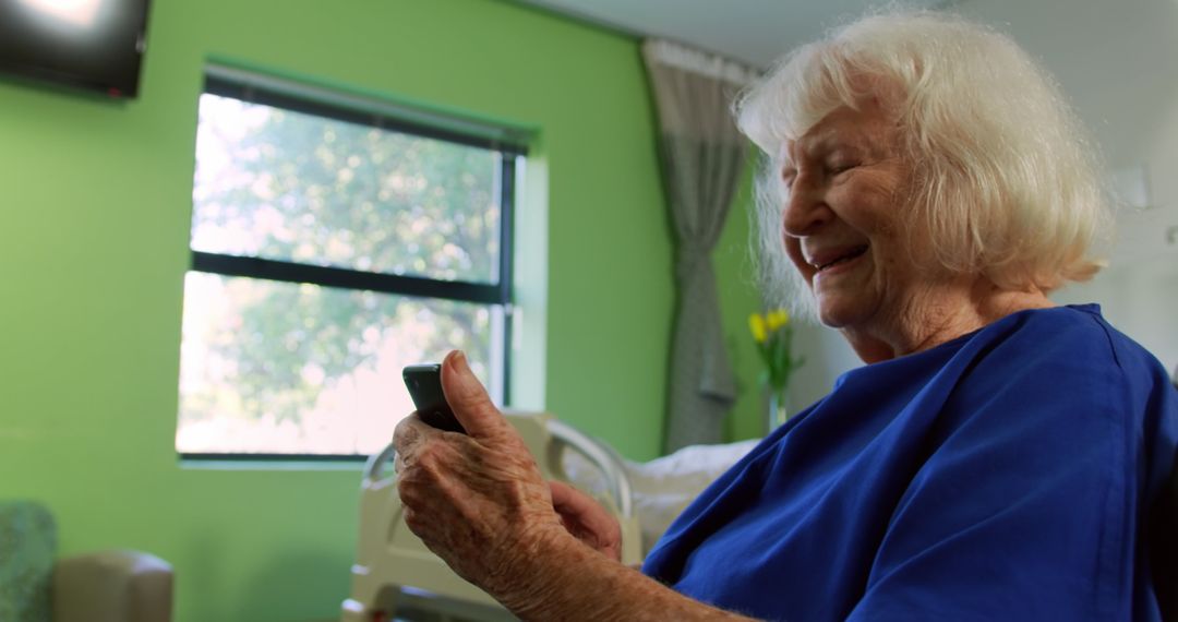 Elderly Woman Smilingly Using Smartphone in Hospital Room - Free Images, Stock Photos and Pictures on Pikwizard.com