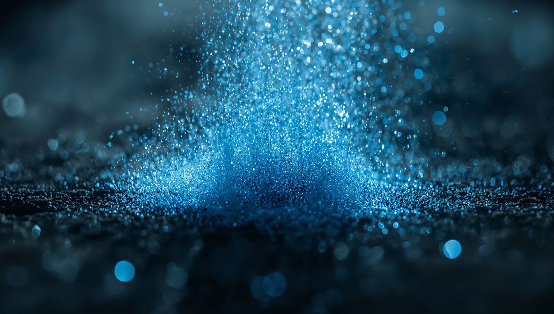 Fine Blue Particles Cascading on Reflective Surface