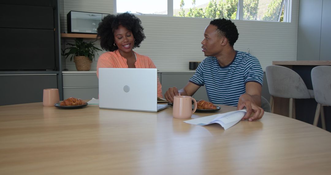 Young Couple Collaborating at Home with Laptop and Documents