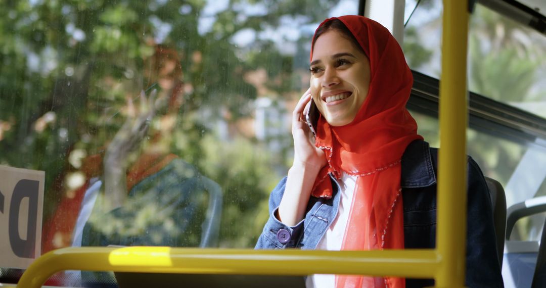 Smiling Young Woman in Red Hijab Talking on Phone Inside Bus - Free Images, Stock Photos and Pictures on Pikwizard.com