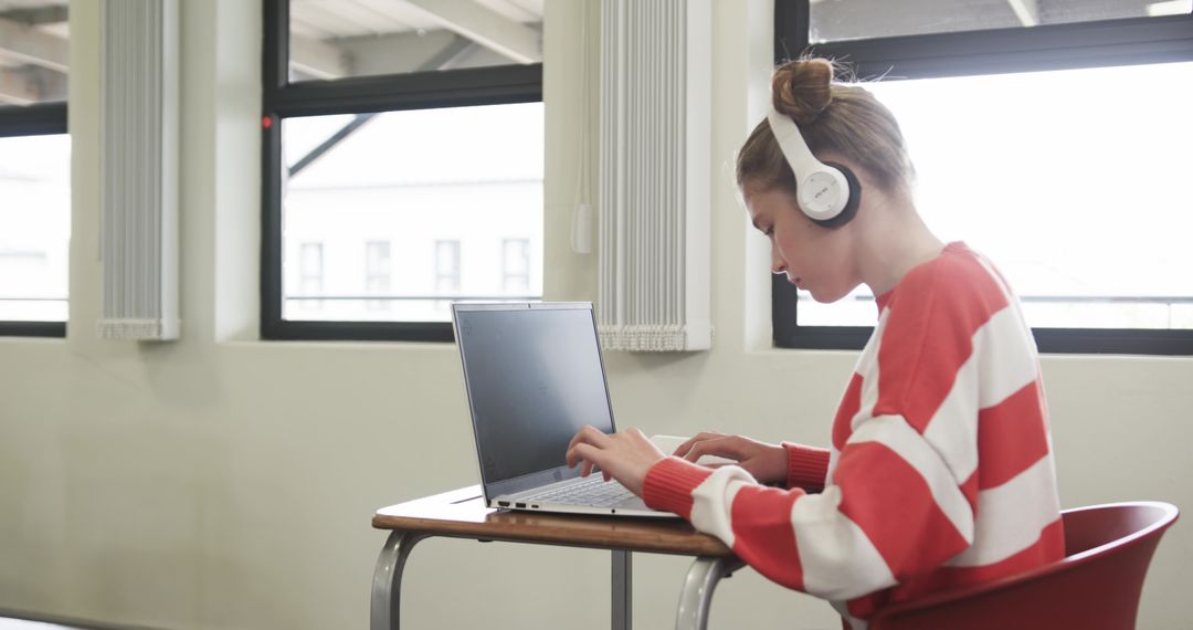Student Focused on Typing with Laptop in Modern Classroom