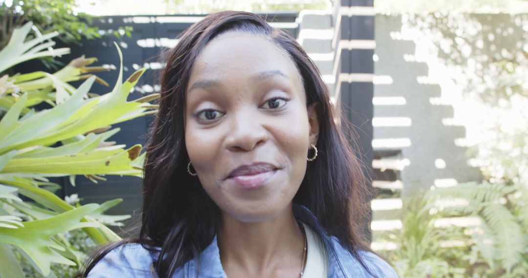 Portrait of Plus Person in a Sunny Courtyard with Greenery and Modern Fence