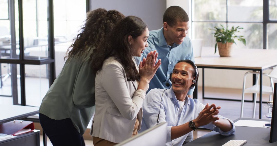Diverse Team Celebrating Achievement Around Computer in Office