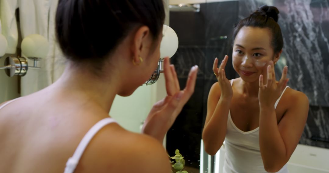 Asian Woman Practicing Skincare Routine in Bathroom
