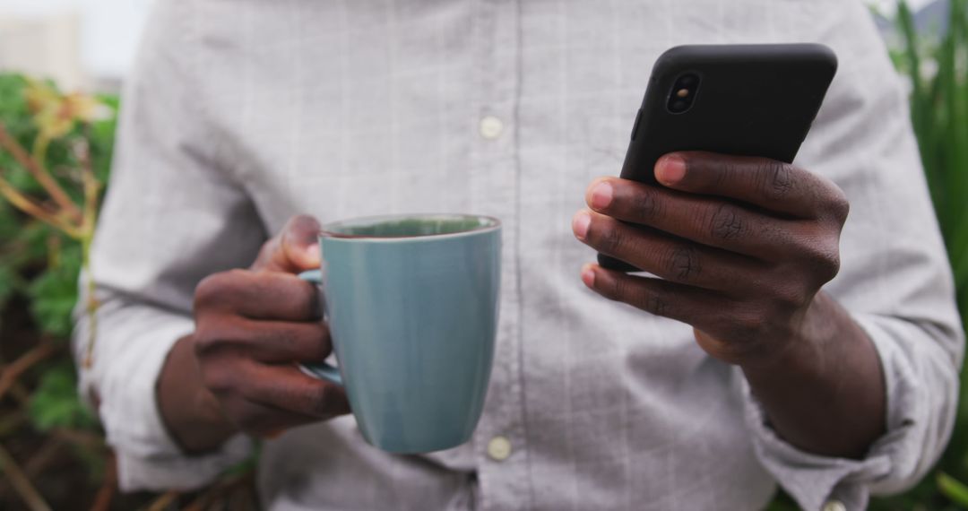 Person Holding Blue Mug and Smartphone in an Outdoor Setting - Free Images, Stock Photos and Pictures on Pikwizard.com