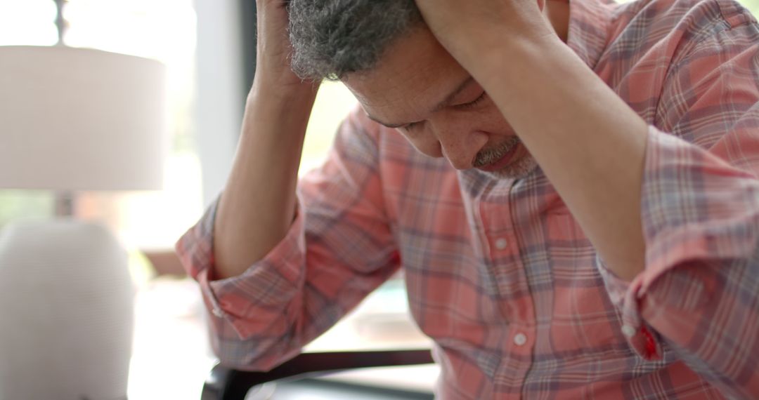 Stressed Mature Man Holding Head in Hands at Home - Free Images, Stock Photos and Pictures on Pikwizard.com