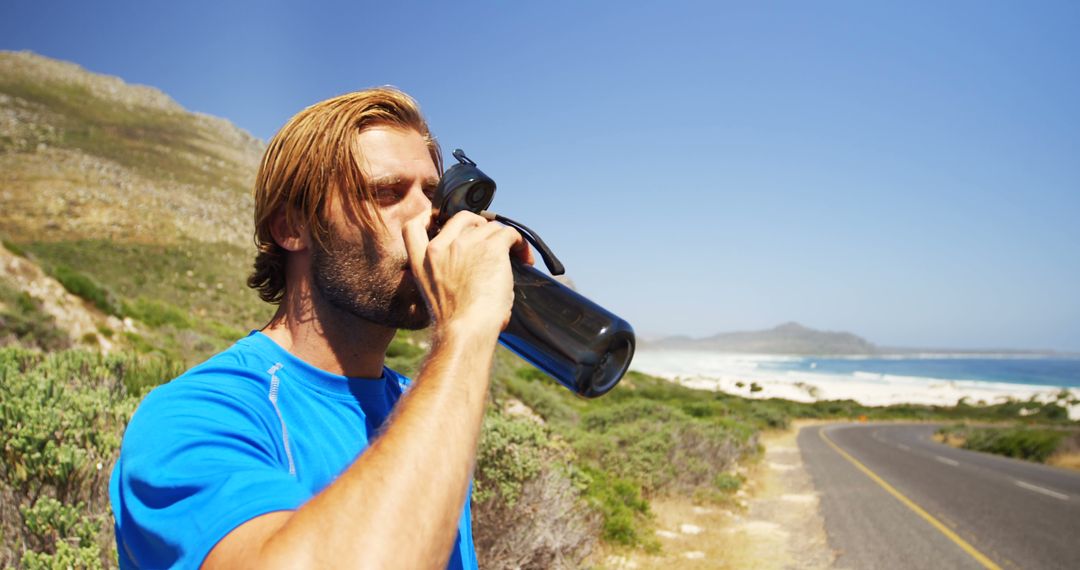 Athletic Man Drinking Water on Coastal Road During Workout - Free Images, Stock Photos and Pictures on Pikwizard.com