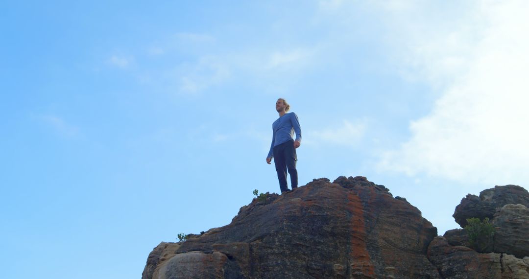 Man Standing on Rocky Mountain Under Clear Blue Sky - Free Images, Stock Photos and Pictures on Pikwizard.com