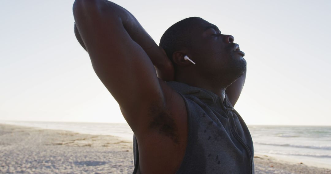 Man stretching with earbuds after beach workout at sunrise - Free Images, Stock Photos and Pictures on Pikwizard.com