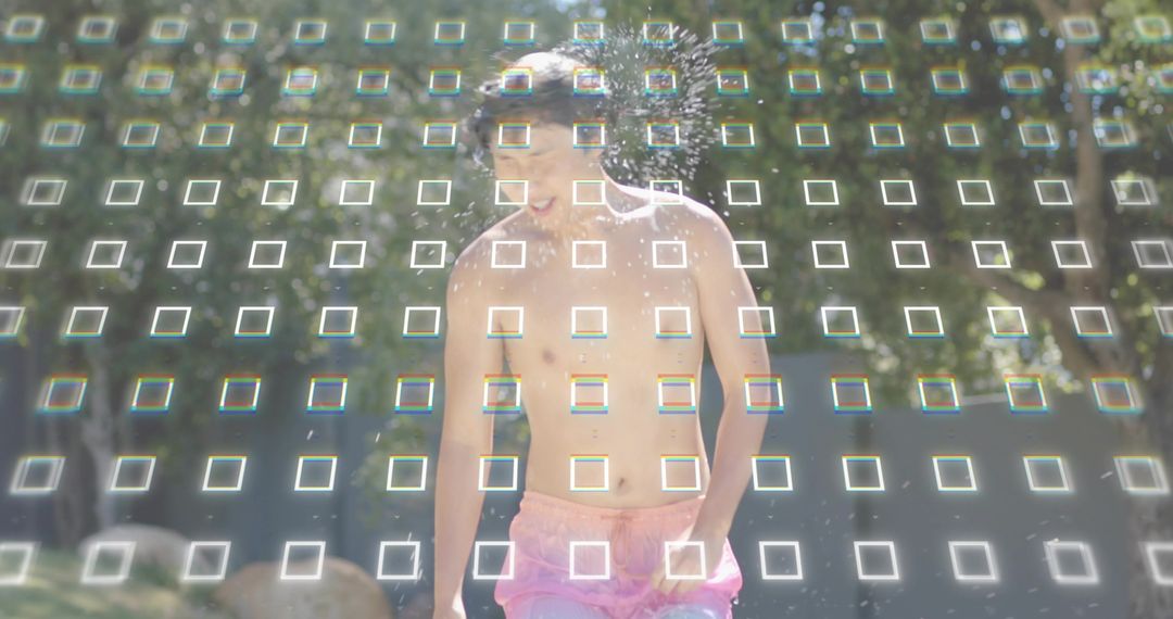 Shirtless Asian man laughing, running through park sprinkler wearing pink trunks