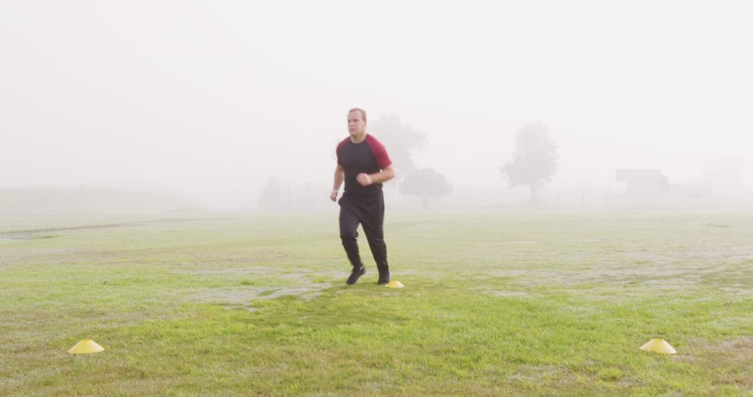 Determined Man Jogging on Misty Field Checking Progress