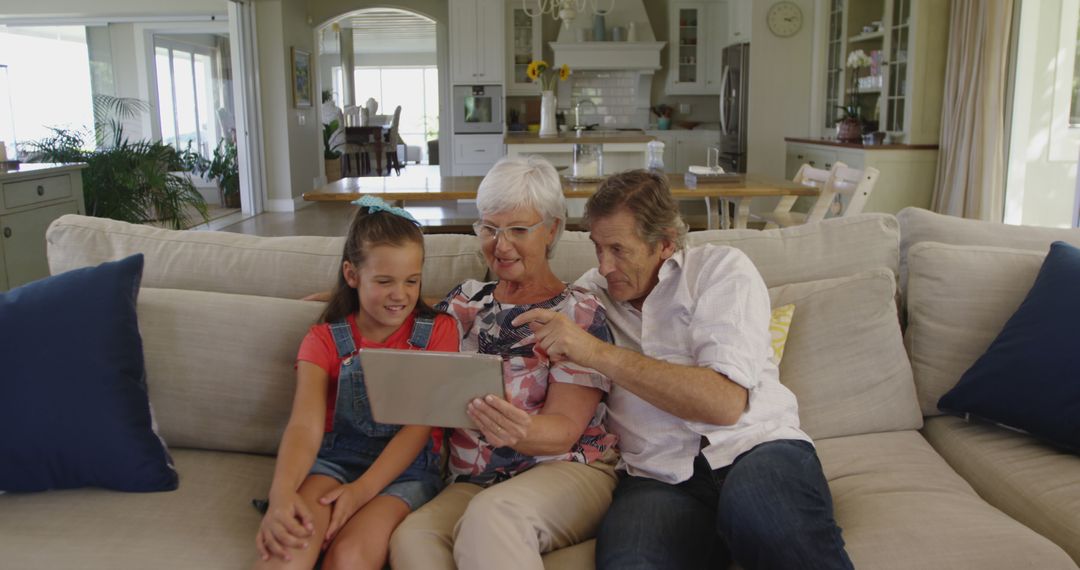 Happy Grandparents with Granddaughter Using Tablet at Home