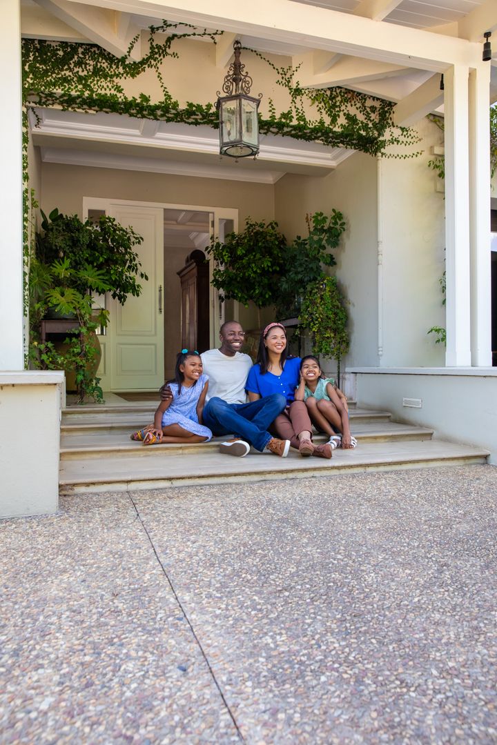 Happy Family Relaxing on Front Porch Steps Amidst Greenery