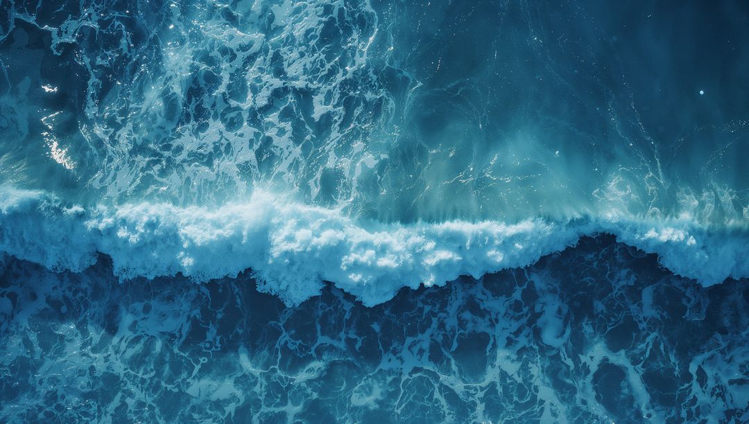 Aerial View of Ocean Waves with Luminous Aqua Foam Patterns