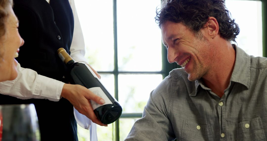 Waiter Serving Wine to Smiling Couple in Restaurant - Free Images, Stock Photos and Pictures on Pikwizard.com