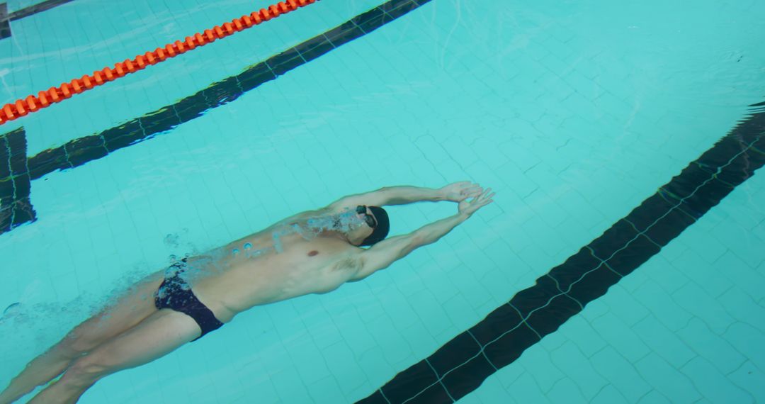 Male Swimmer Performing Backstroke at Indoor Pool - Free Images, Stock Photos and Pictures on Pikwizard.com