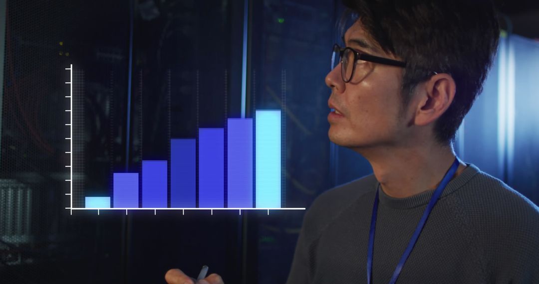 Asian IT Engineer Analyzing Data in Server Room with Digital Graph Overlay