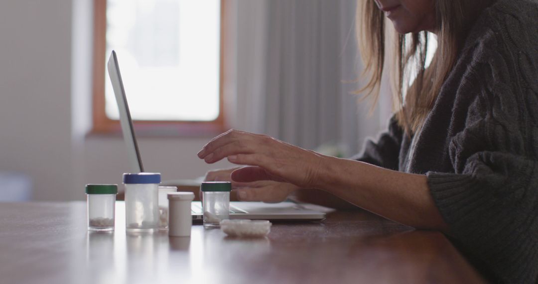 Woman Using Laptop with Medication Bottles on Desk - Free Images, Stock Photos and Pictures on Pikwizard.com