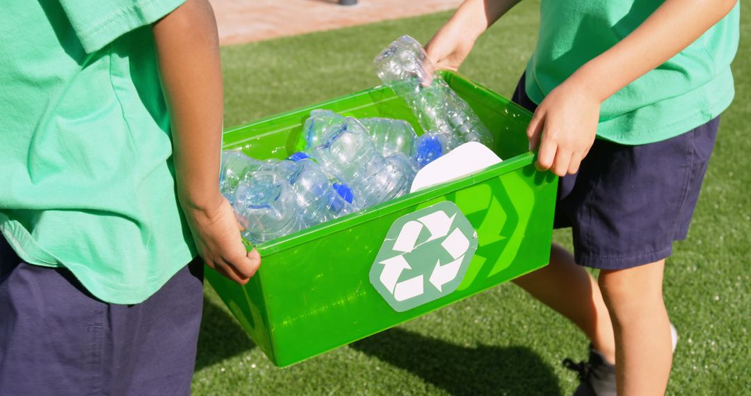 Schoolchildren Carrying Recyclables in Green Bin Outdoors